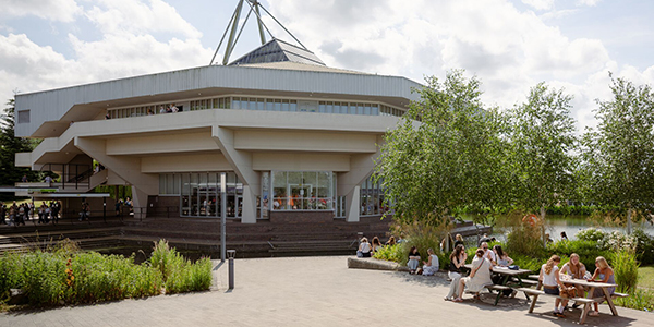External shot of Central Hall with students sat on benches outside